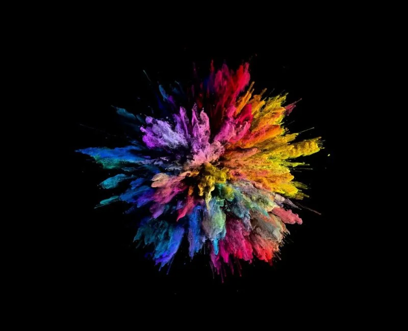 Vibrant burst of multicoloured powder symbolising creative graphic design on a black background